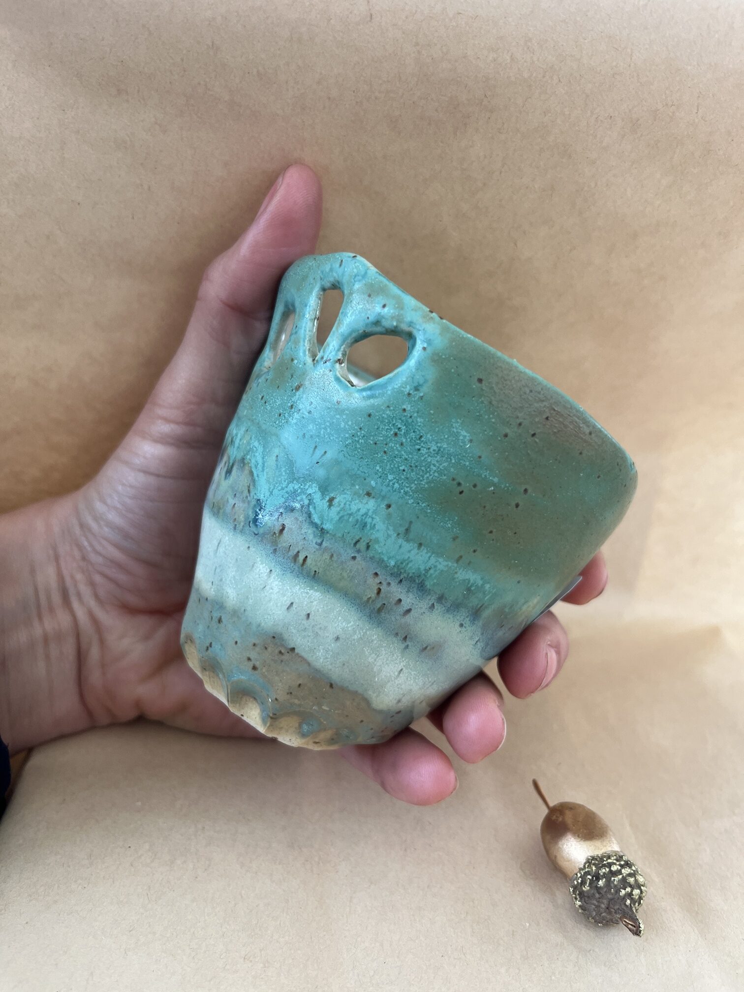 Tasse sans anse en grès avec émaux en cascade de vert, tenue dans une main pour montrer sa taille idéale pour toutes vos boissons chaudes