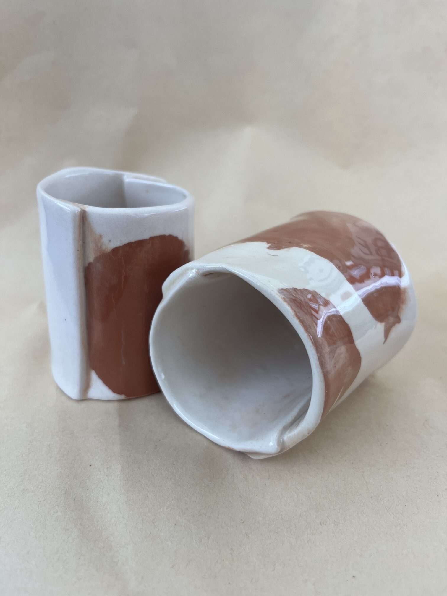deux tasse marbrée en faience rouge et blanche présentée pour qu'on y voir le côté et l'intérieur